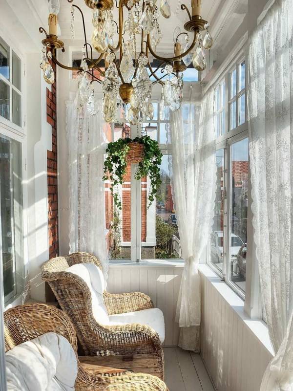 белый балкон с люстрой и плетеной мебелью